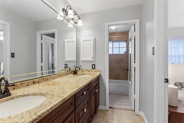 a bathroom with a granite countertop double vanity sink and mirror