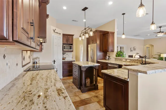 a large kitchen with stainless steel appliances kitchen island granite countertop a sink and a refrigerator