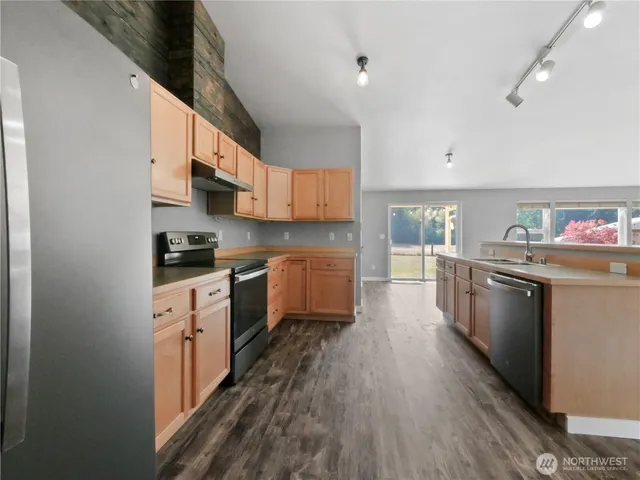 a kitchen with stainless steel appliances a stove top oven a sink a refrigerator and cabinets