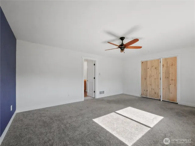 an empty room with closet and ceiling fan