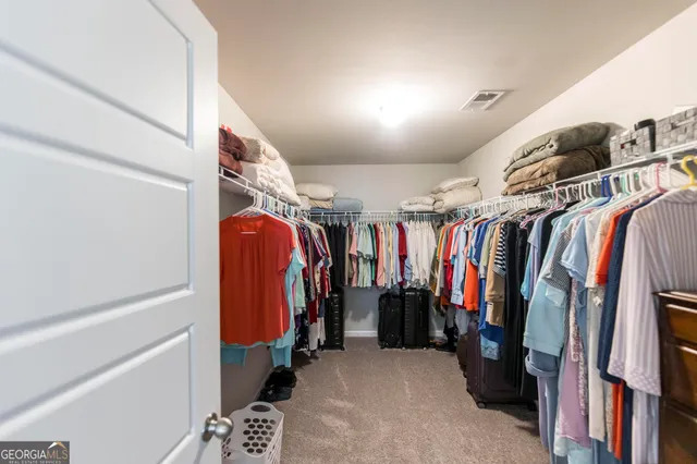 a view of walk in closet with clothes and shoes