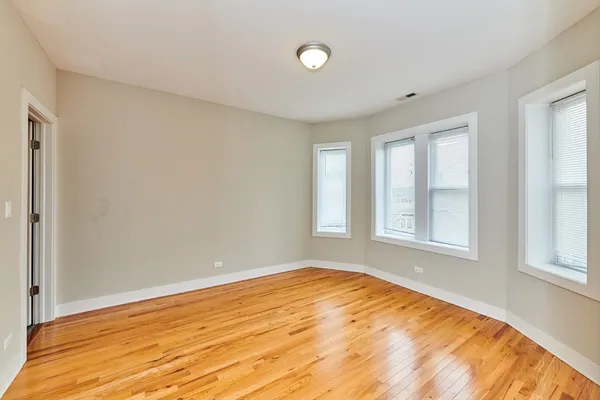 a view of empty room with wooden floor and fan