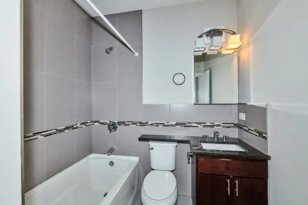 a bathroom with a granite countertop toilet sink and mirror