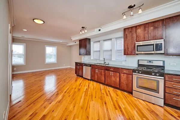 a large kitchen with stainless steel appliances granite countertop a stove a sink dishwasher and a microwave oven with wooden floor