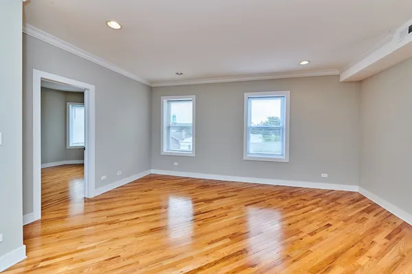 a view of empty room with wooden floor and fan