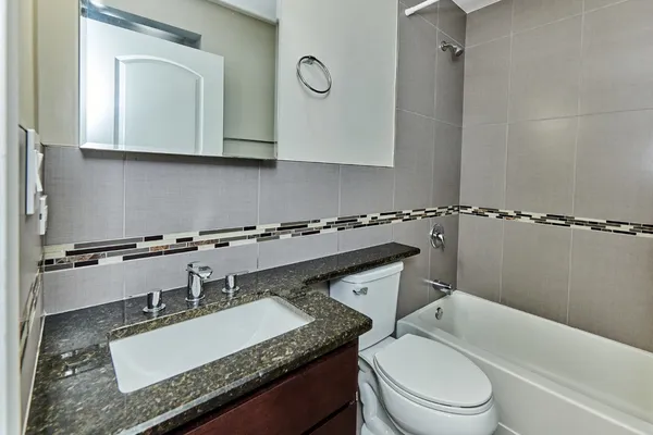 a bathroom with a granite countertop sink mirror vanity and toilet