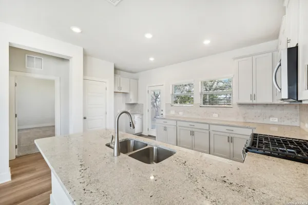 a kitchen with granite countertop a sink a stove and cabinets