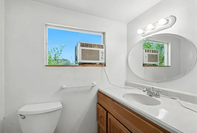 a bathroom with a toilet a sink a mirror and a window