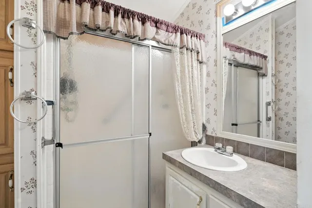a bathroom with a granite countertop sink a mirror a vanity and a shower