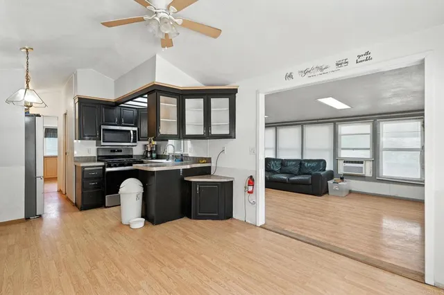 a kitchen with stainless steel appliances kitchen island granite countertop a refrigerator a sink dishwasher a stove and a dining table with wooden floor