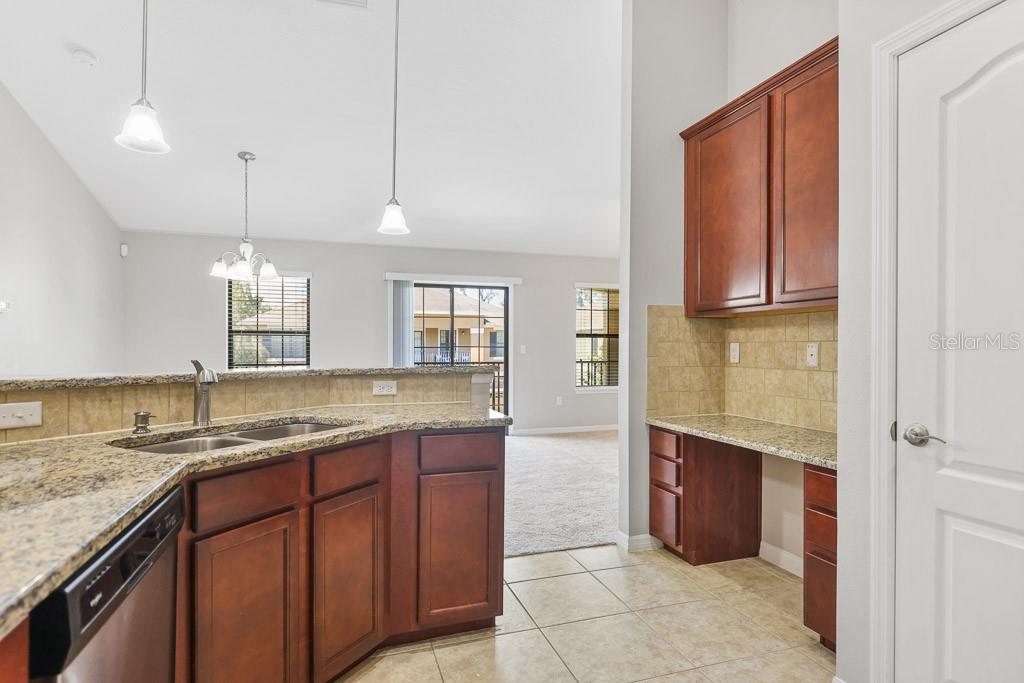 5738 Kingletsound Lithia, FL 33547 - Photo 11 of 32 a kitchen with kitchen island granite countertop wooden cabinets a sink and dishwasher