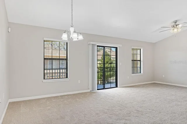 an empty room with windows and chandelier fan