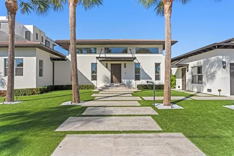 a front view of a house with a yard and palm tree