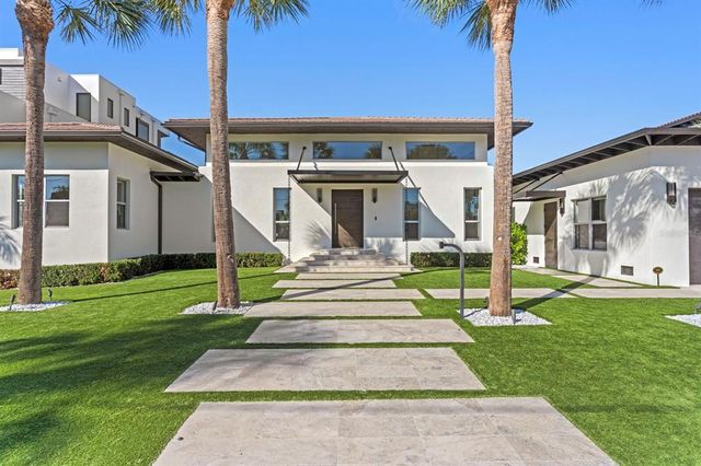 a front view of a house with a yard and palm tree