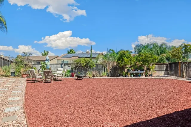 a backyard of a house with table and chairs under an umbrella