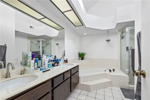 a bathroom with a tub sink double vanity granite tub shower and a mirror