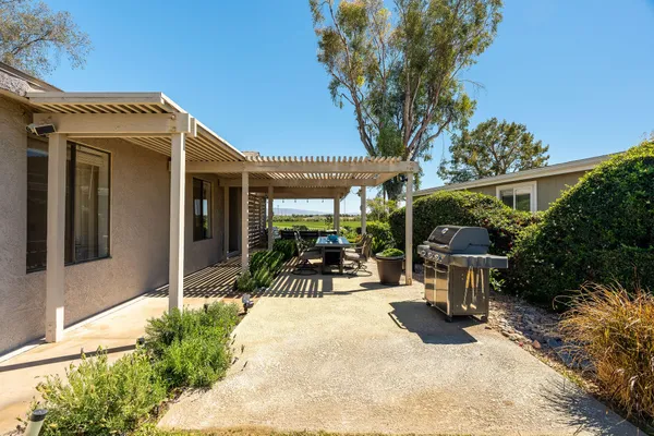 a view of backyard of house with outdoor seating and barbeque oven