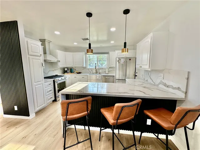 a kitchen with stainless steel appliances kitchen island granite countertop a table chairs in it and wooden floors