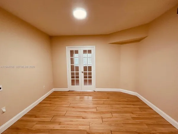 a view of empty room with wooden floor and fan