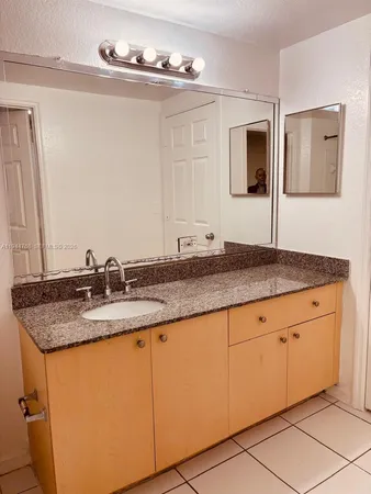 a bathroom with a granite countertop sink and a mirror