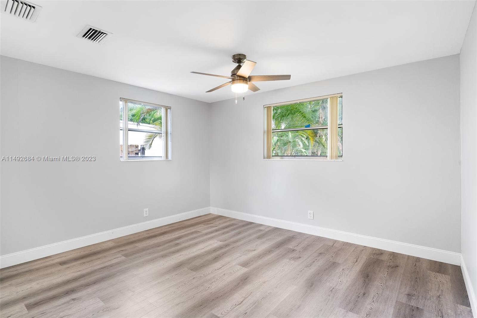 5893 Williamson Road Jupiter, FL 33458 - Photo 22 of 31 an empty room with wooden floor ceiling fan and windows