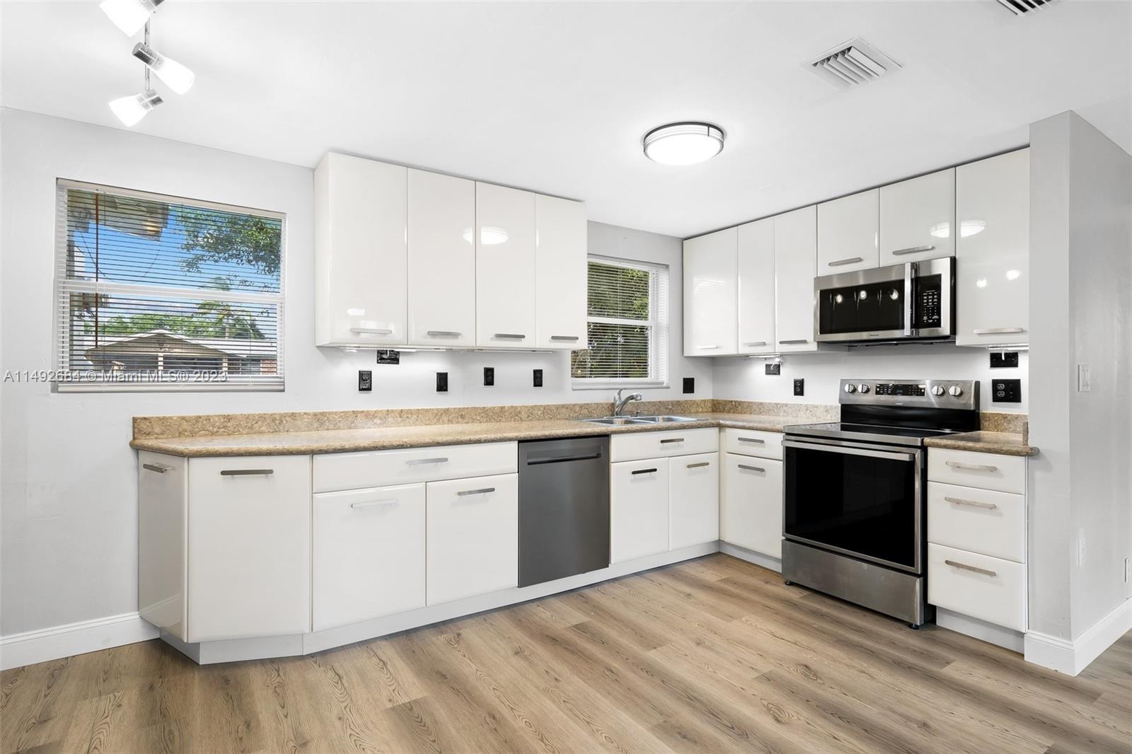 5893 Williamson Road Jupiter, FL 33458 - Photo 5 of 31 a kitchen with stainless steel appliances granite countertop a stove top oven a sink dishwasher a refrigerator and a microwave oven with wooden floor