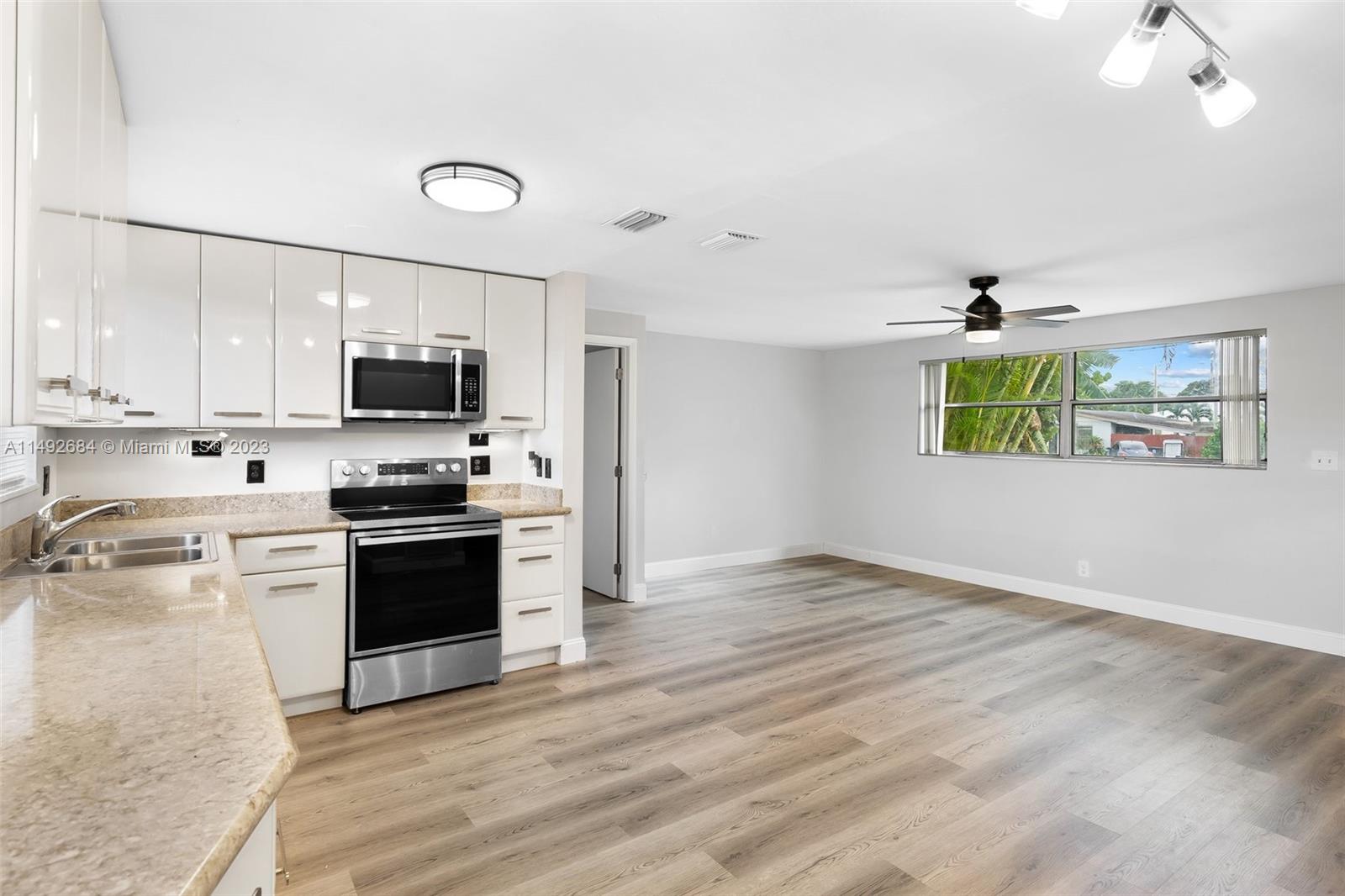 5893 Williamson Road Jupiter, FL 33458 - Photo 6 of 31 a kitchen with kitchen island granite countertop a stove a sink and a microwave