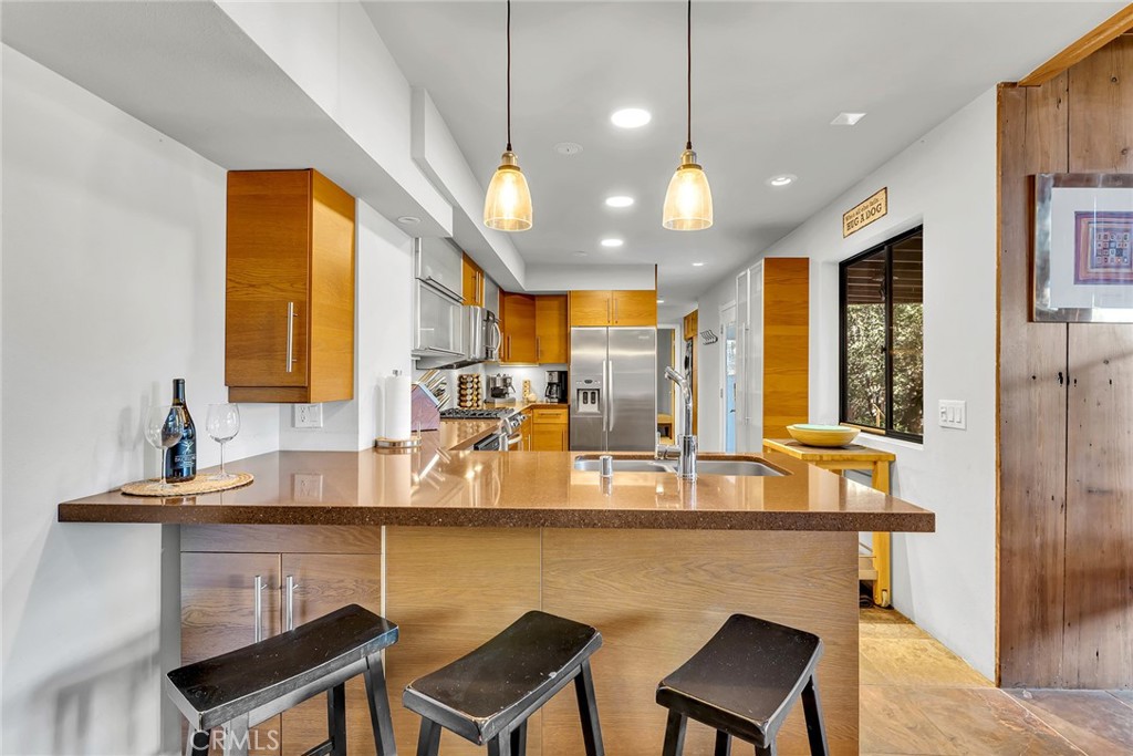 53580 Jeffery Pine Road Idyllwild, CA 92549 - Photo 15 of 61 a dining hall with stainless steel appliances kitchen island granite countertop a table chairs and a refrigerator