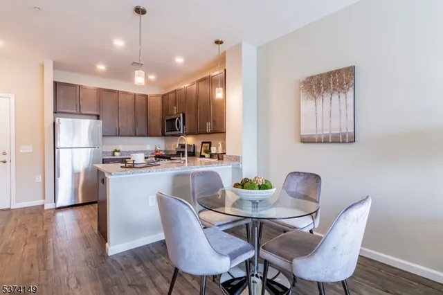 a kitchen with a dining table chairs refrigerator and wooden floor