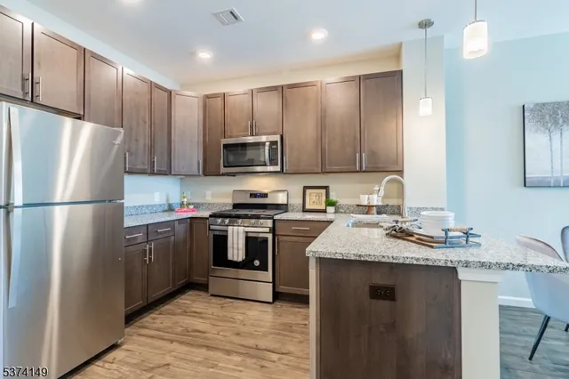 a kitchen with stainless steel appliances granite countertop a refrigerator stove a sink and a microwave