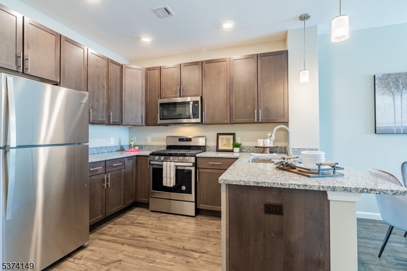 54 North Main Street, Unit 413 Wharton, NJ 07885 - Photo 8 of 15 a kitchen with stainless steel appliances granite countertop a refrigerator stove a sink and a microwave