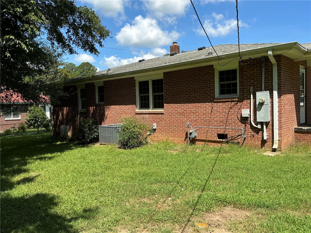 609 West Geer Street Honea Path, SC 29654 - Photo 3 of 18 Classic brick construction details this rear exterior overlooking a grassy yard under sunny skies.