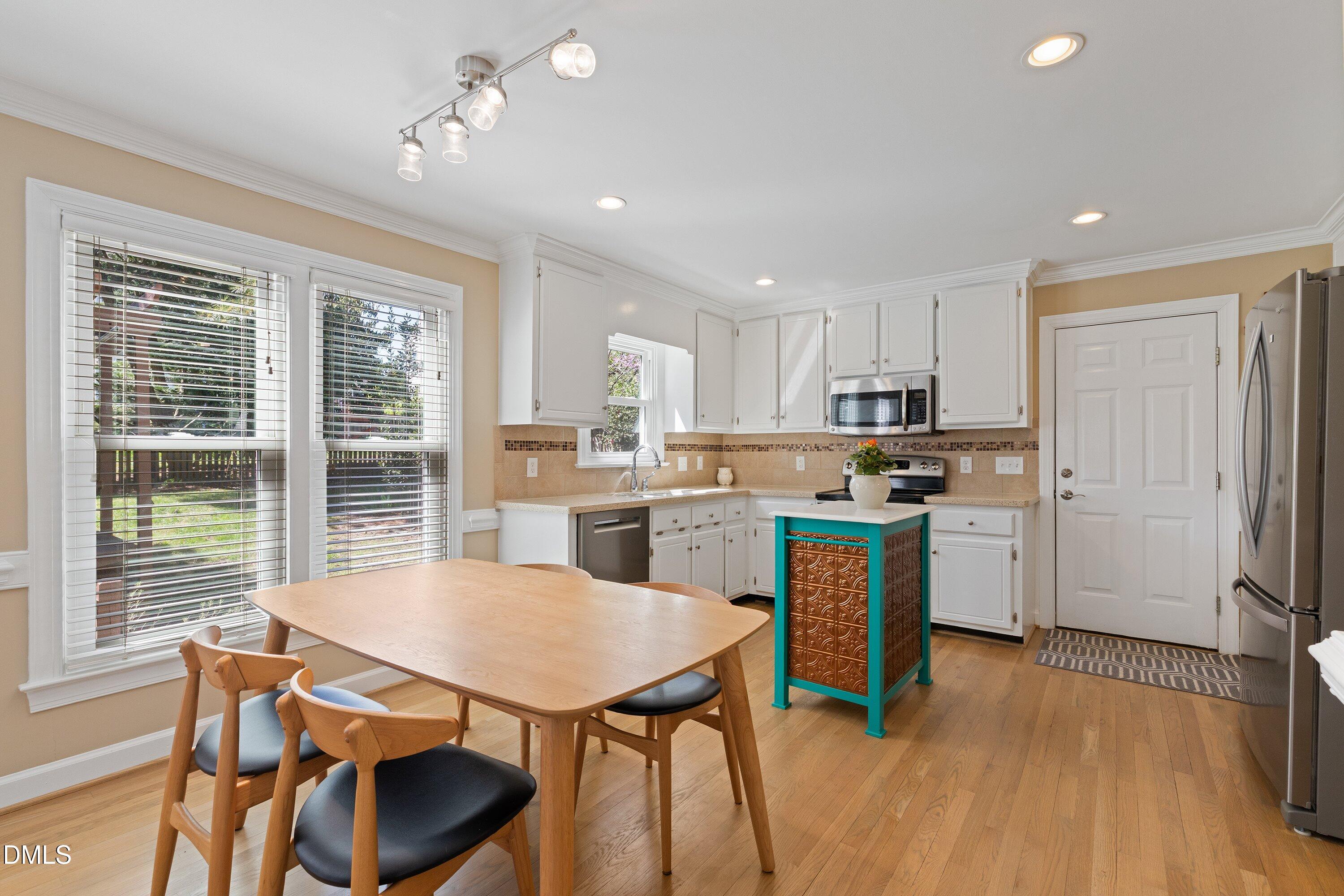501 Samara Street Apex, NC 27502 - Photo 13 of 77 a kitchen with a table chairs refrigerator and microwave