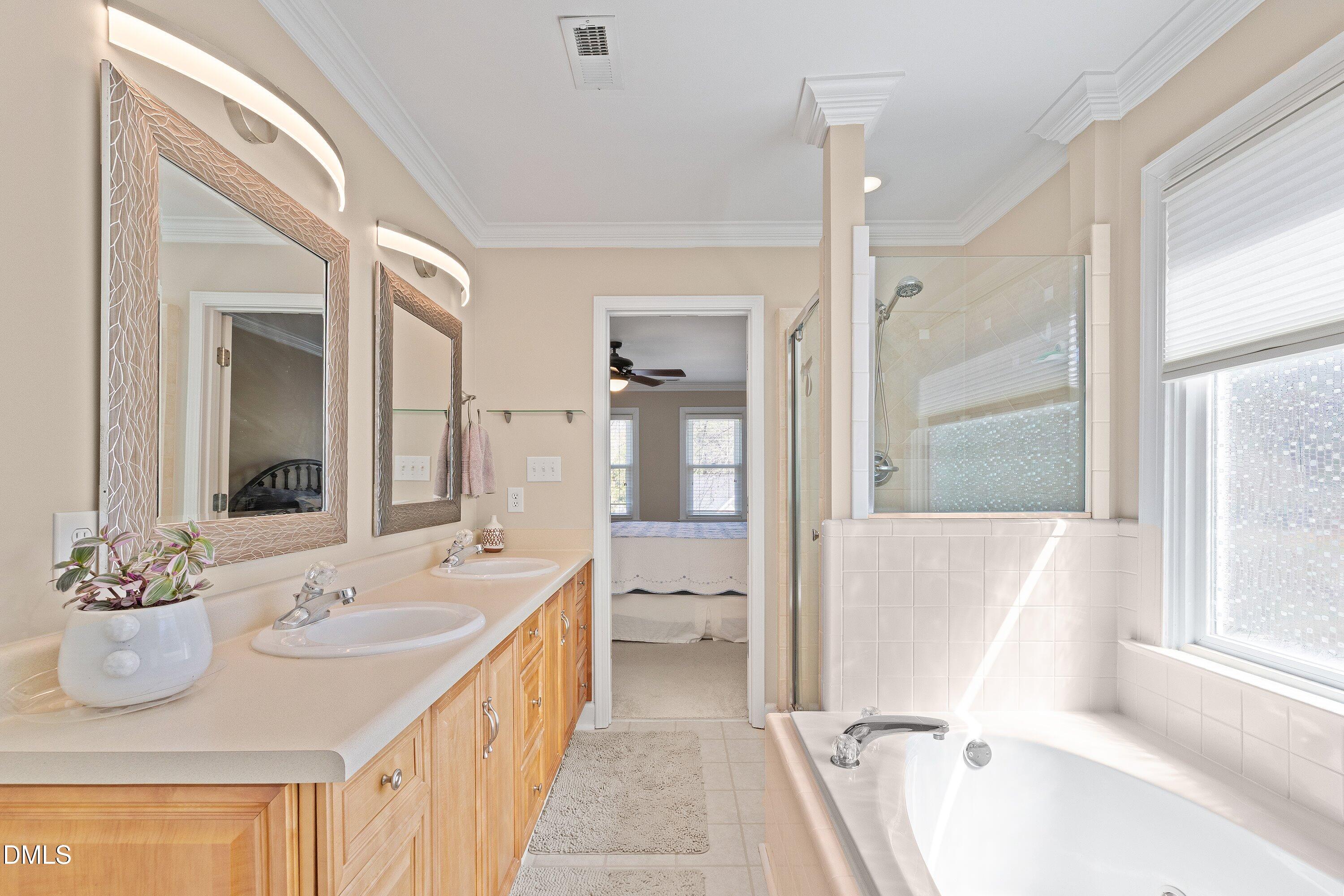 501 Samara Street Apex, NC 27502 - Photo 33 of 77 a bathroom with a sink a mirror and a bathtub next to a window