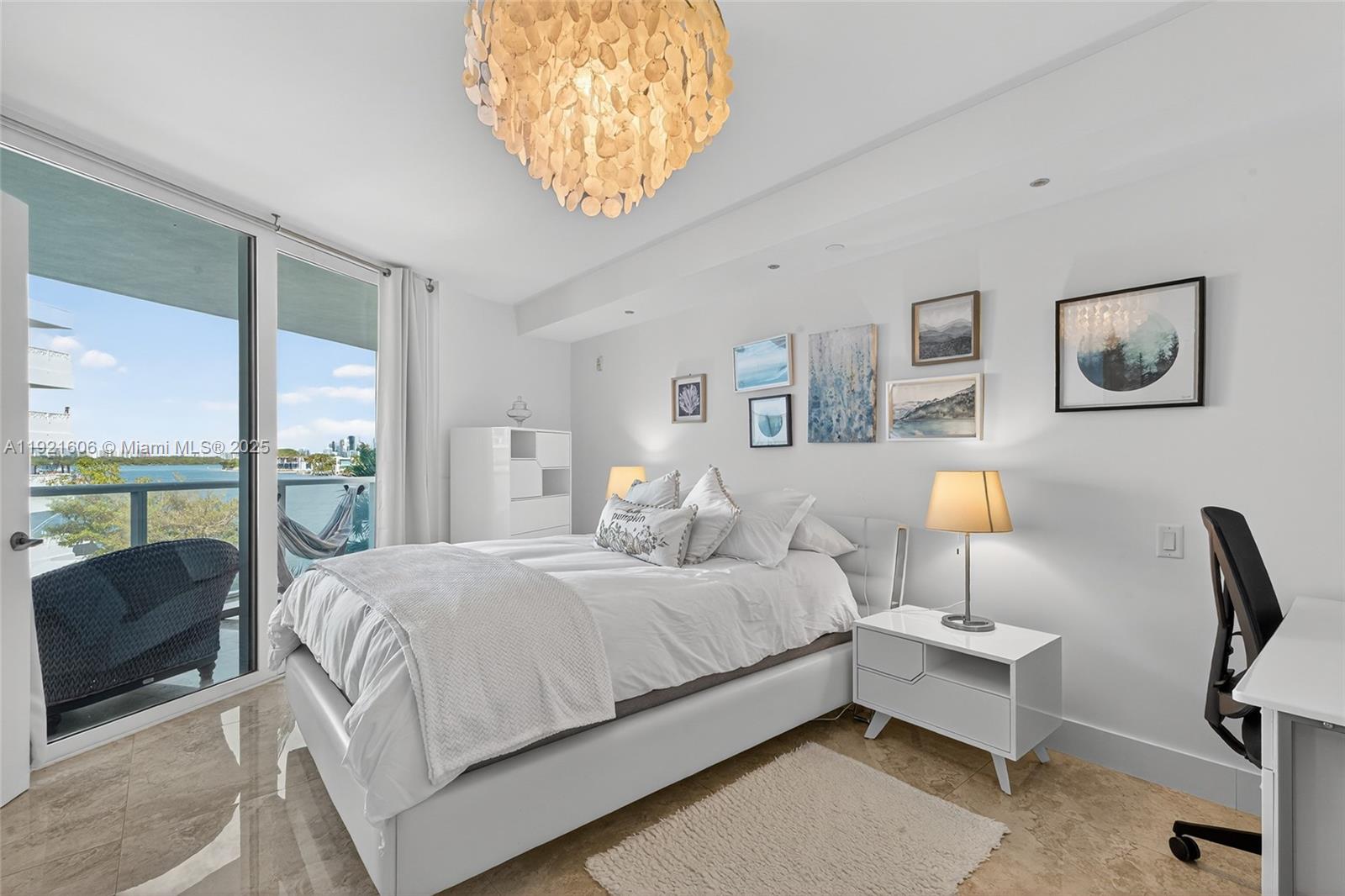 9821 East Bay Harbor Drive, Unit 402 Bay Harbor Islands, FL 33154 - Photo 15 of 34 a bedroom with a bed and a chandelier