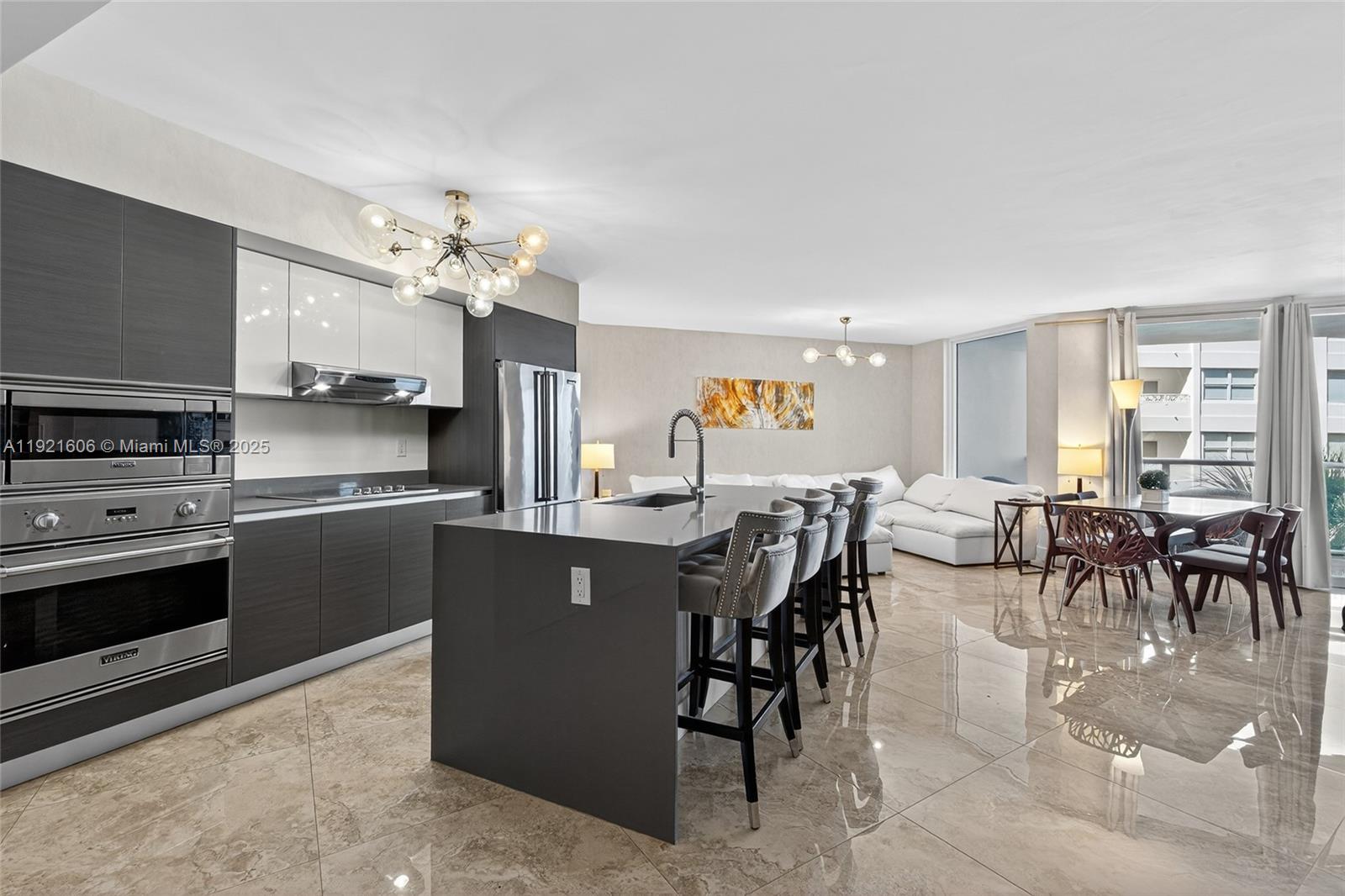 9821 East Bay Harbor Drive, Unit 402 Bay Harbor Islands, FL 33154 - Photo 4 of 34 a kitchen with stainless steel appliances kitchen island granite countertop a table chairs sink and cabinets