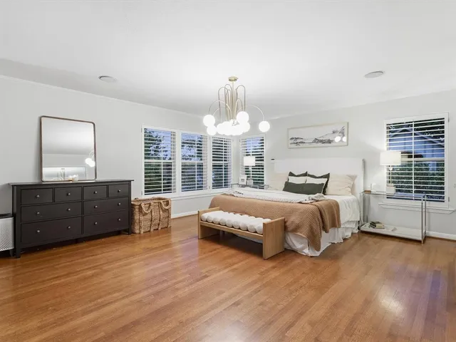 a spacious bedroom with a bed and wooden floor