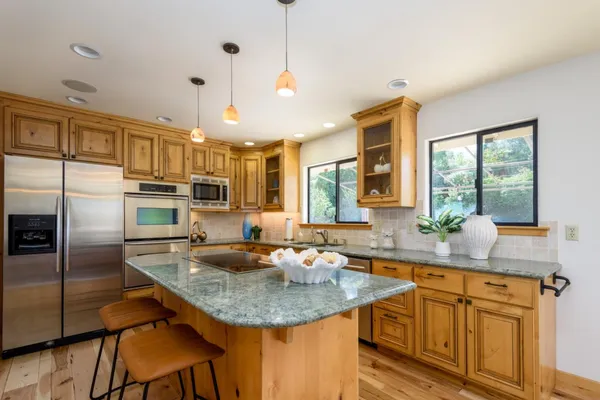 a kitchen with granite countertop kitchen island stainless steel appliances a sink stove and refrigerator