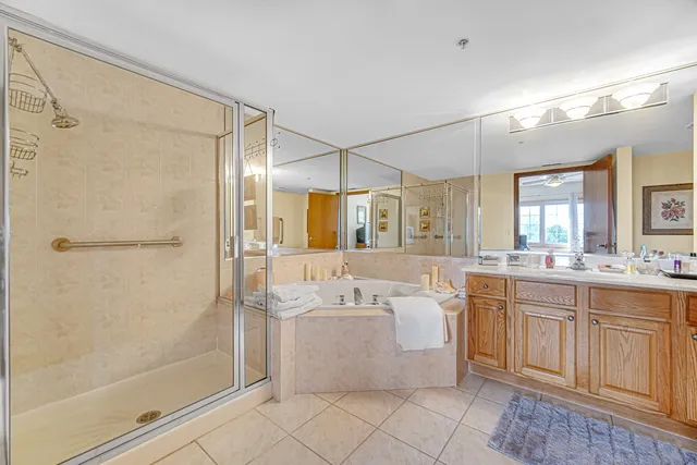 a bathroom with a bathtub shower sink vanity and mirror
