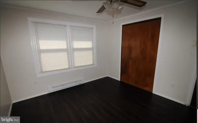 an empty room with wooden floor closet and windows