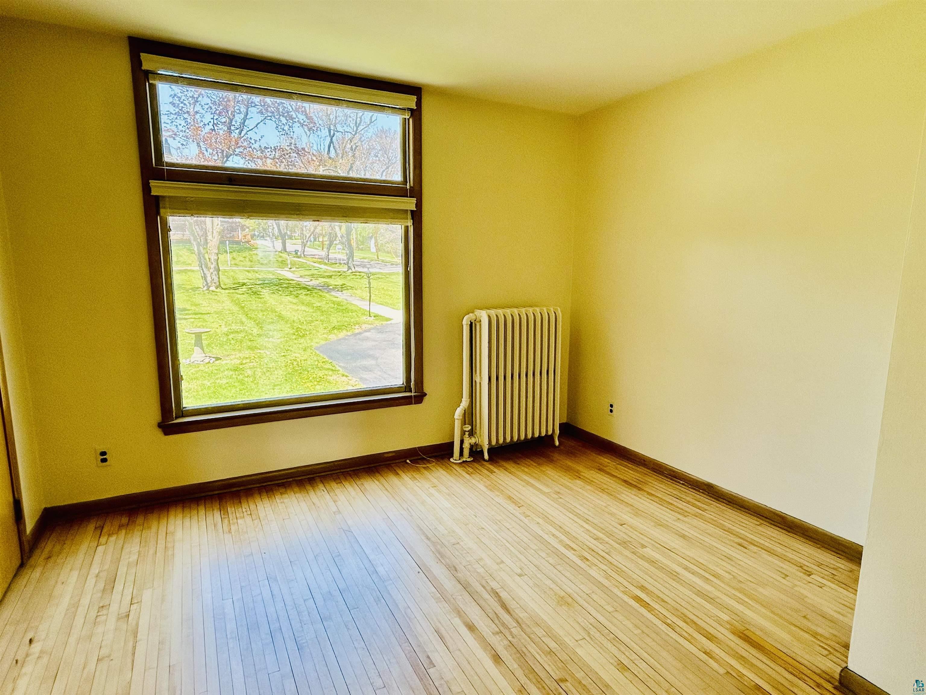 5090 London Road, Unit 1 Duluth, MN 55804 - Photo 21 of 54 Bright interior space featuring a large picture window with a transom, wood-finish flooring, and a classic radiator
