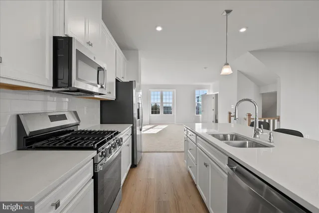 a kitchen with stainless steel appliances a sink a stove and cabinets