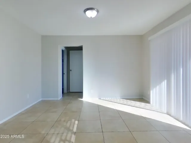 an empty room with windows and chandelier fan