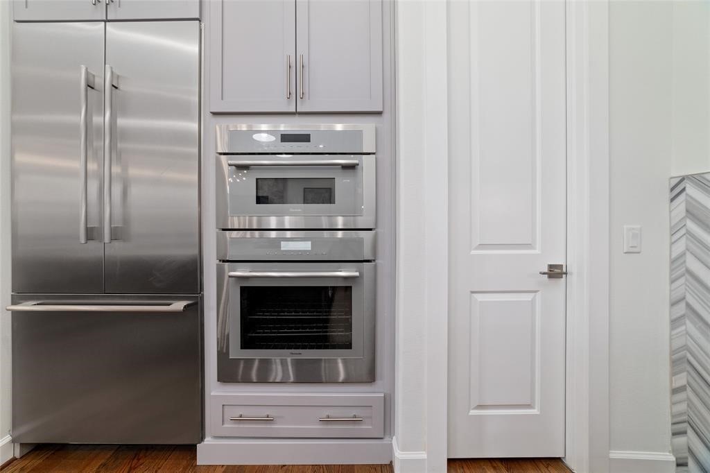 710 Delano Street, Unit A Houston, TX 77003 - Photo 11 of 32 This kitchen features modern stainless steel appliances, including a double-door refrigerator and built-in ovens. The cabinetry is sleek and complements the contemporary design, while the hardwood floors add warmth to the space.