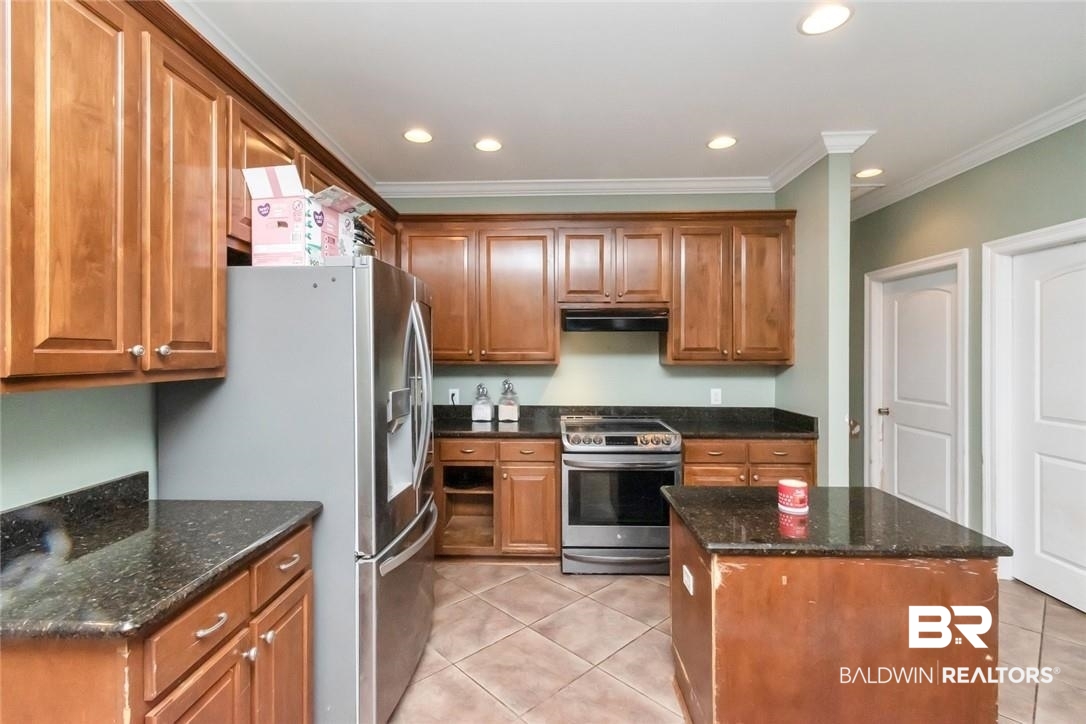 7170 Pierson Drive Mobile, AL 36619 - Photo 7 of 29 Kitchen featuring appliances with stainless steel finishes, light tile patterned flooring, a kitchen island, dark stone counters, and ornamental molding