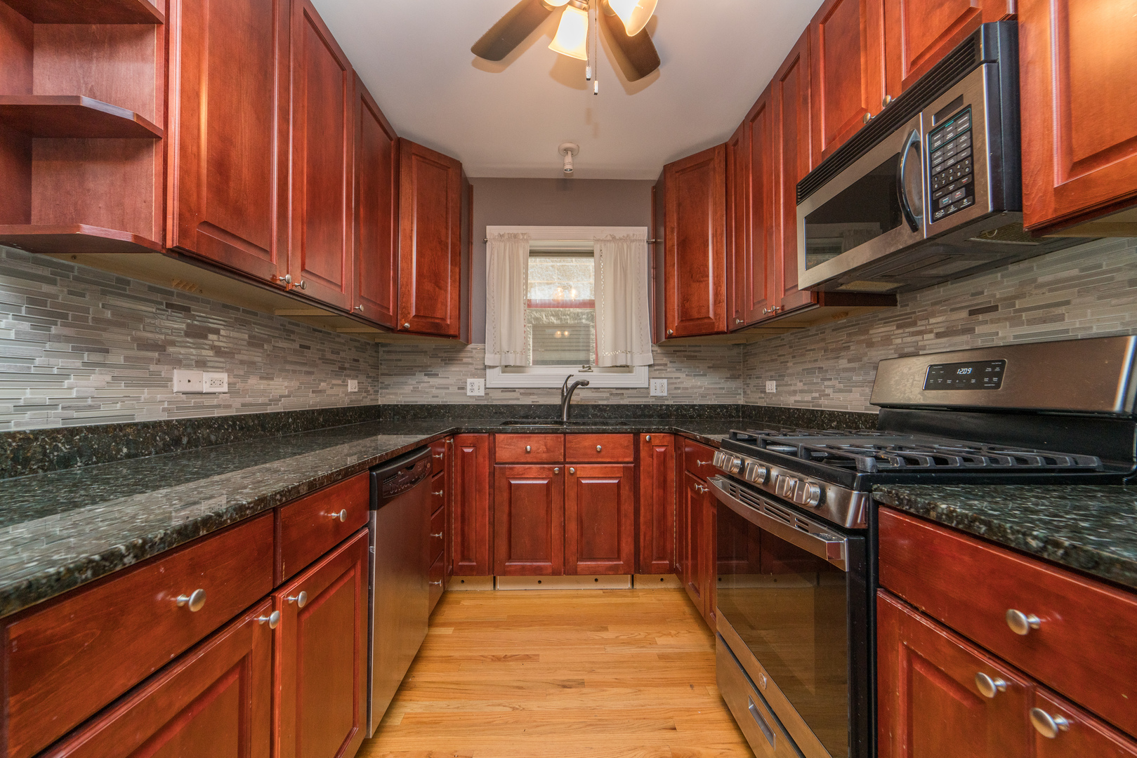 7509 West Irving Park Road, Unit 1 Chicago, IL 60634 - Photo 7 of 28 a kitchen with stainless steel appliances granite countertop wooden cabinets a stove top oven a sink and dishwasher
