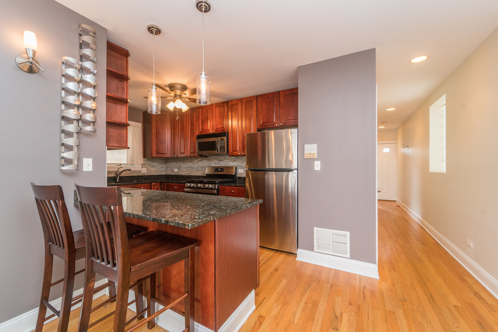 7509 West Irving Park Road, Unit 1 Chicago, IL 60634 - Photo 8 of 28 a kitchen with granite countertop wooden floors and stainless steel appliances