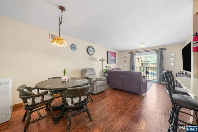 a living room with stainless steel appliances furniture wooden floor and a kitchen view