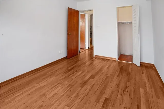 a view of an empty room with wooden floor and closet