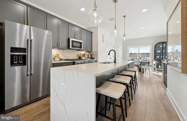 a kitchen with stainless steel appliances granite countertop a refrigerator a stove a sink a dining table and chairs with wooden floor